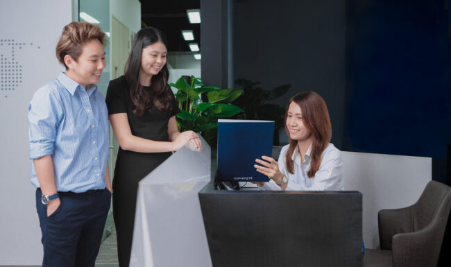 Three white-collar workers smiling in office for company photography