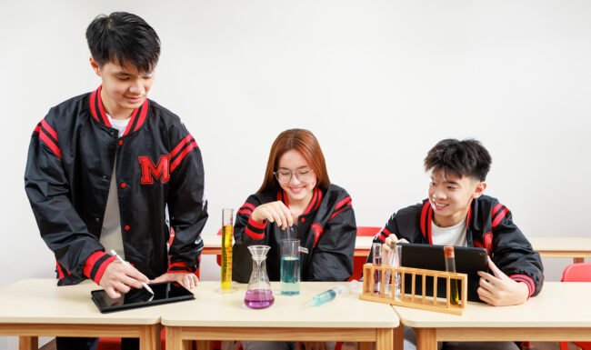 Three students at desk conducting research for a photography